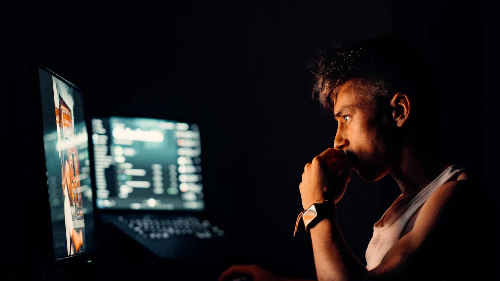 A trader at two monitors in a dark room